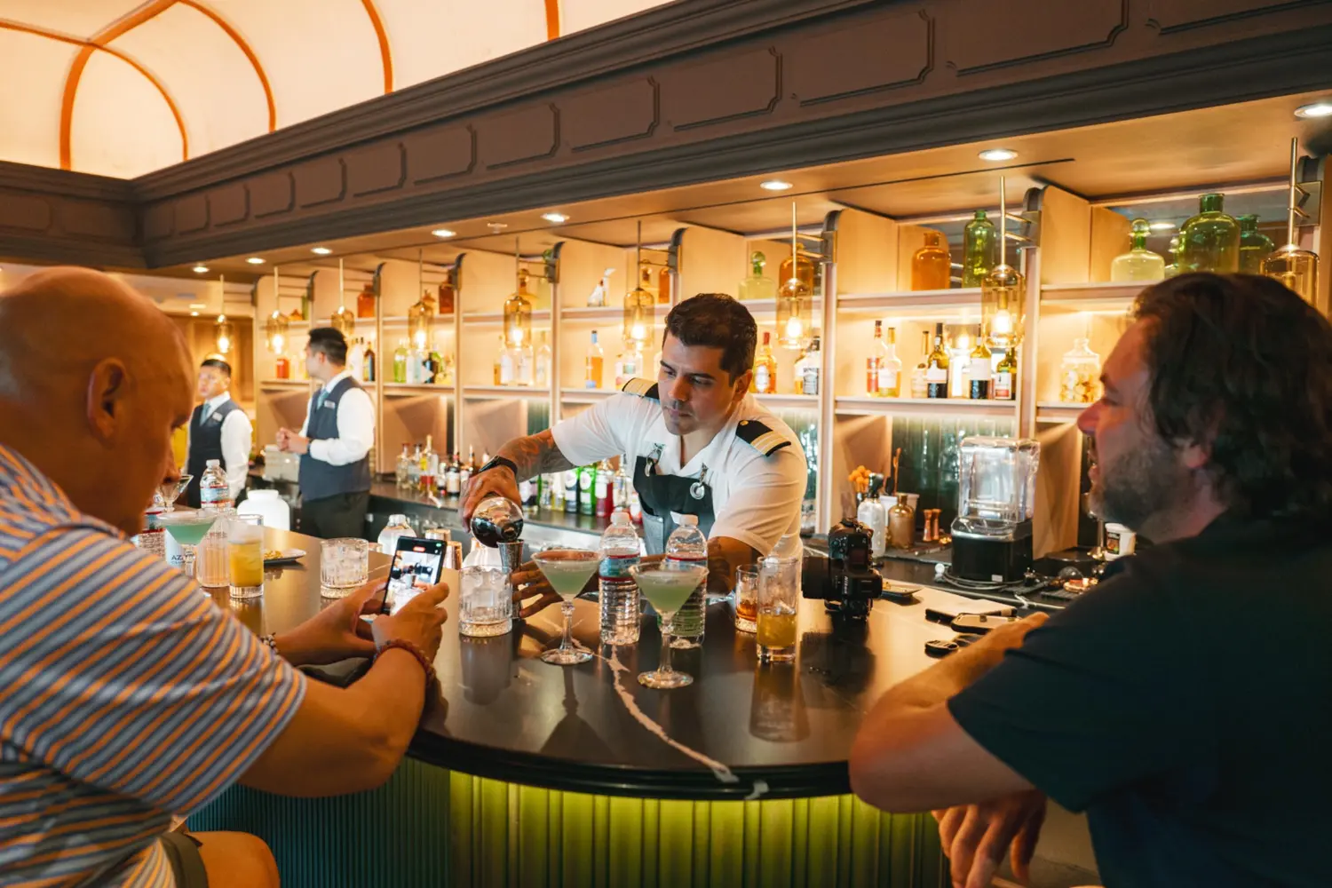 Bartender preparing cocktails for guests at Atlas Bar aboard Azamara