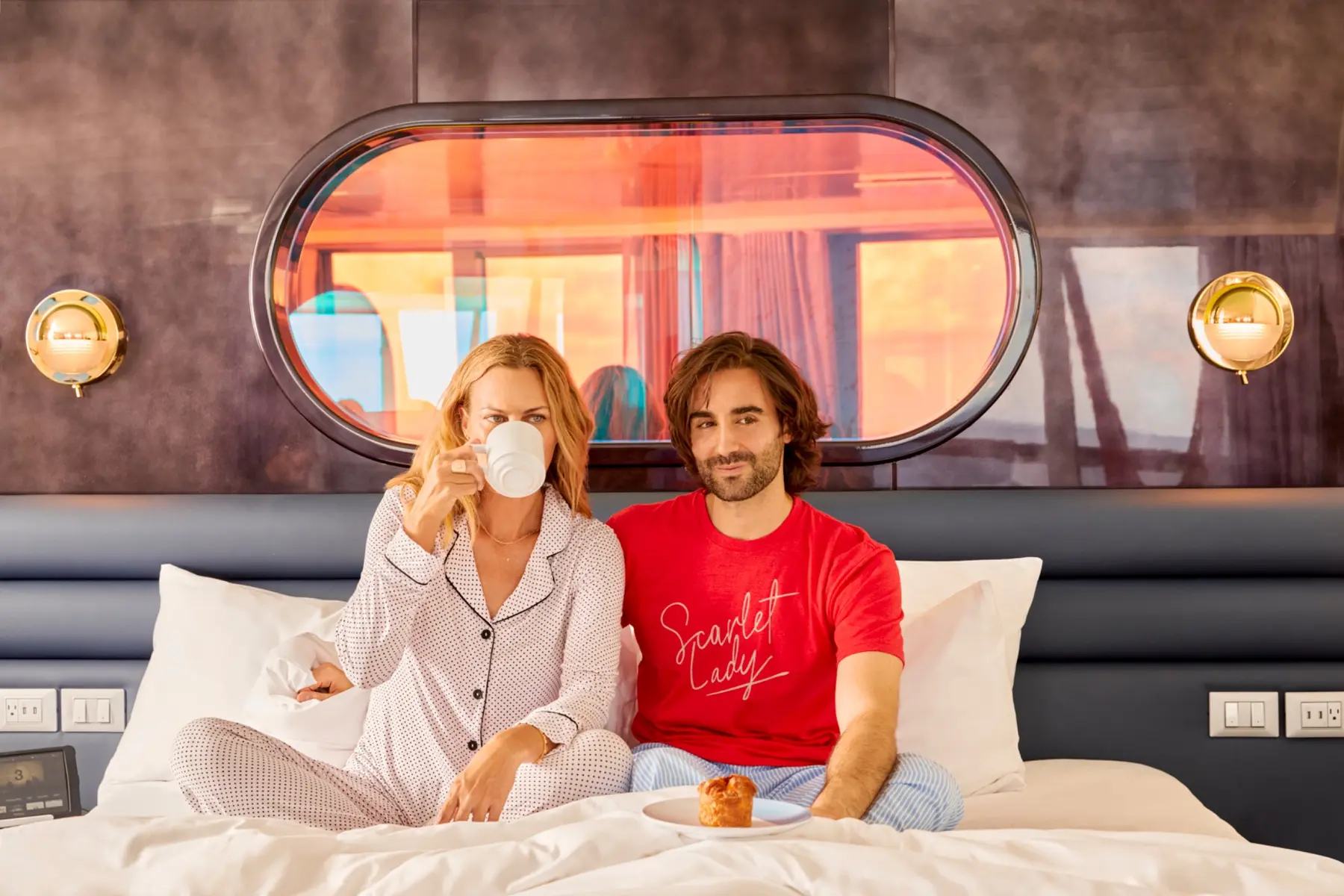 Couple relaxing in bed inside a Virgin Voyages RockStar Quarter